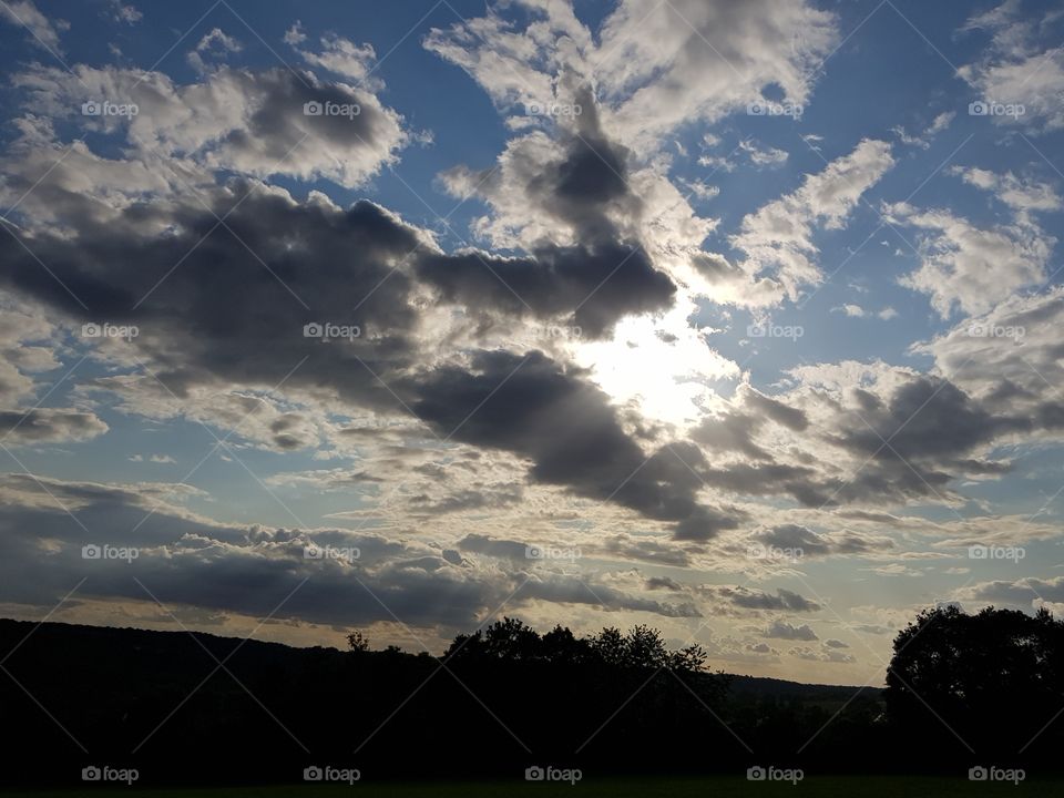 the sun is shining in the middle of the clouds in the middle of nature