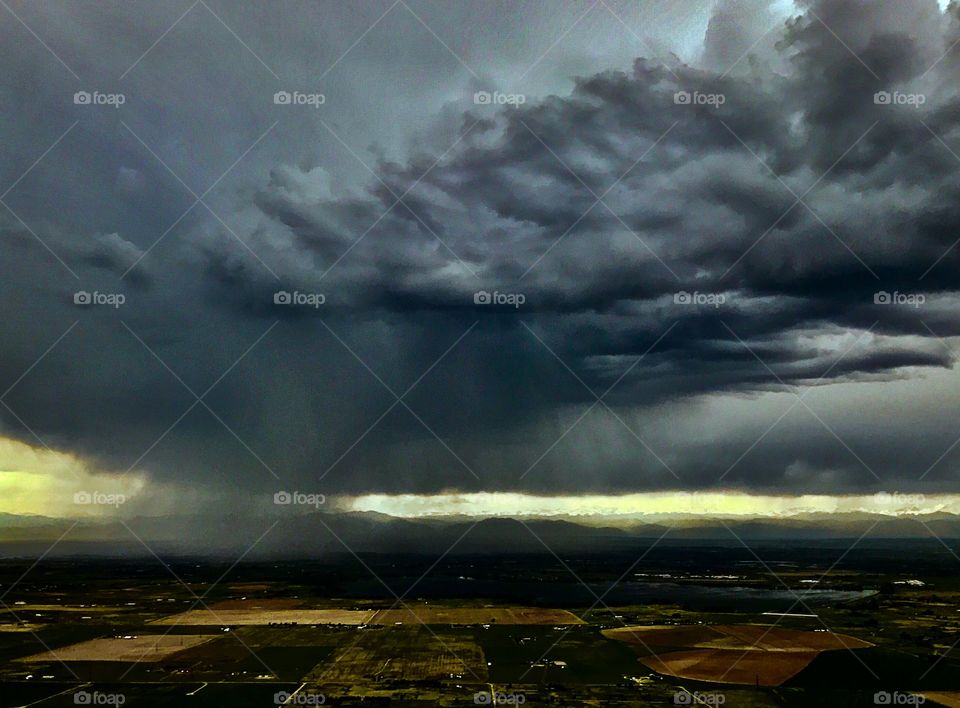 Wall cloud and rain over the plains on approach to Denver International Airport just before sunset. 