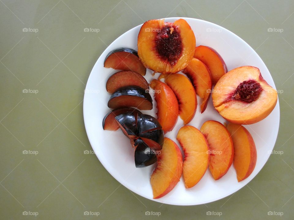 White plate with sliced peach, nectarine and plum