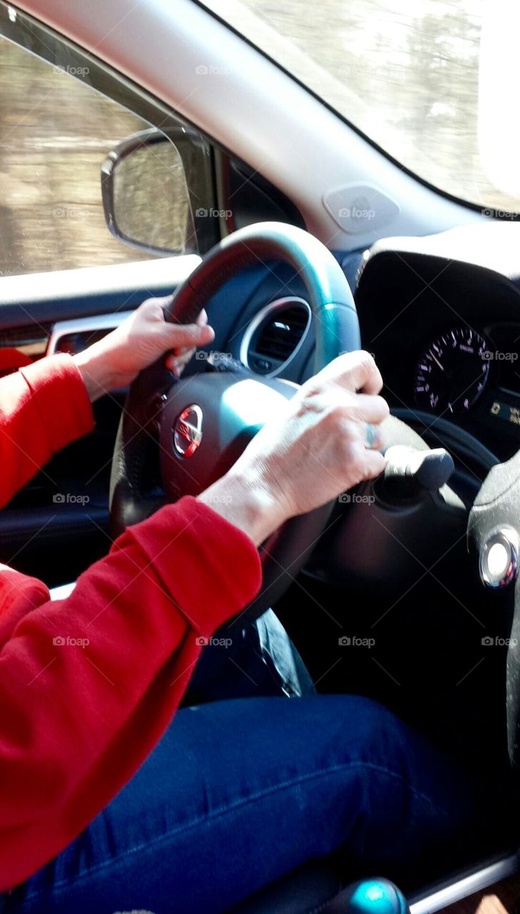 Driving car down highway, hands on steering wheel.