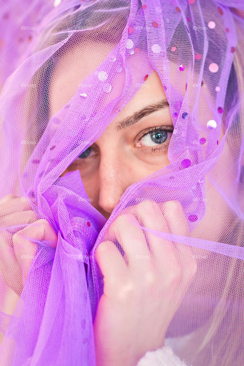 Portrait of beautiful girl with blue eyes wrapped in purple clothes