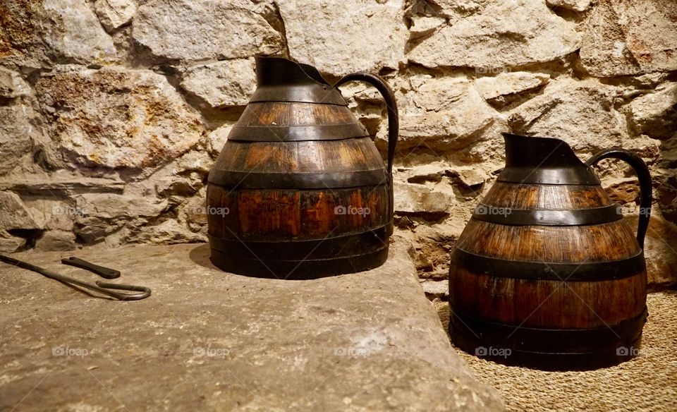 Wooden jugs against a stone wall