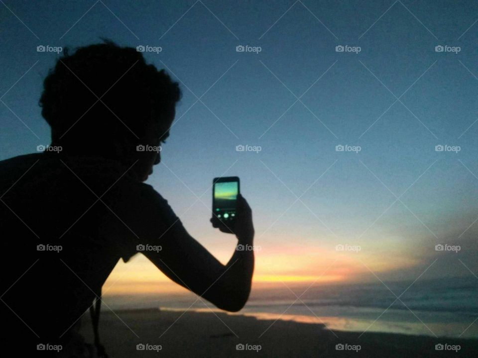 a young boy took a selfie and look at the magic sunset at essaouira city in Morocco.