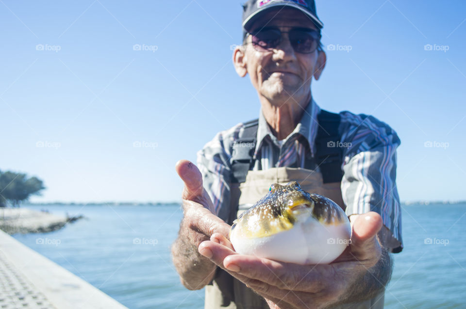 A local fisherman holds up a blowfish 