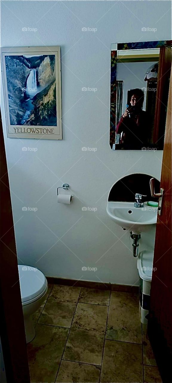 This is one bathrooms in the beautiful house in „Bavaria“, Germany. The porcelain sink is has a half round mirror behind it to complement the shape. A rectangular mirror and an elegant art poster complete the design. 2023. Hypnotic Productions