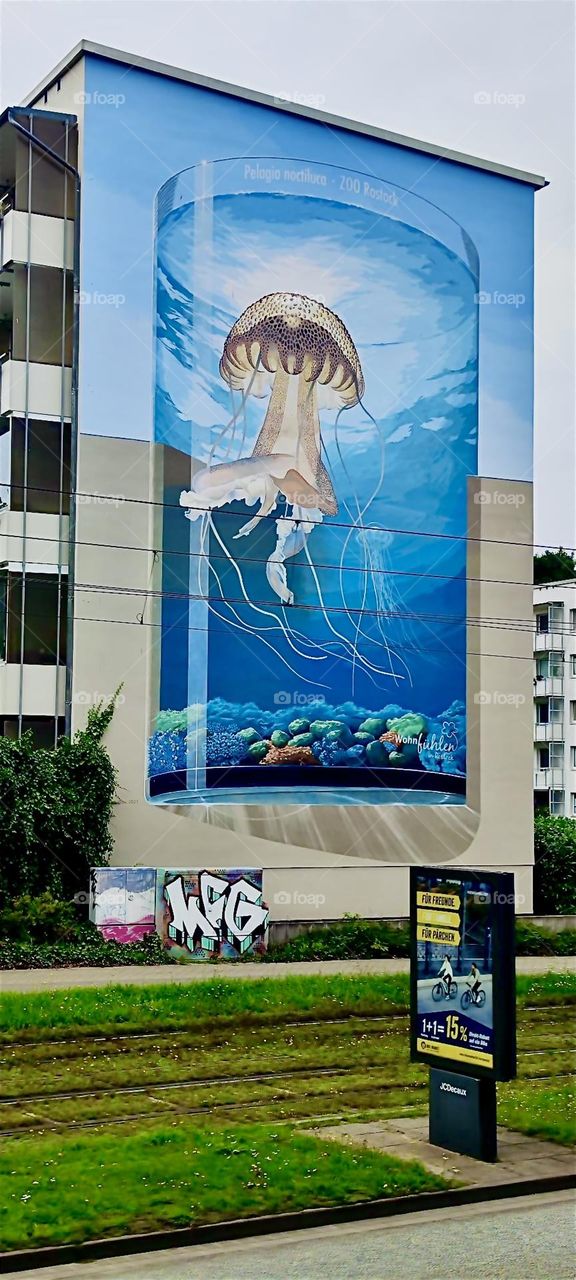 A gigantic mural adorns a high rise building in “Rostock” by the “Baltic Sea” in former “East Germany”. The topic is surreal and it contains a nuclear bomb. That is all that can be said with certainty. 2023. Hypnotic Productions
