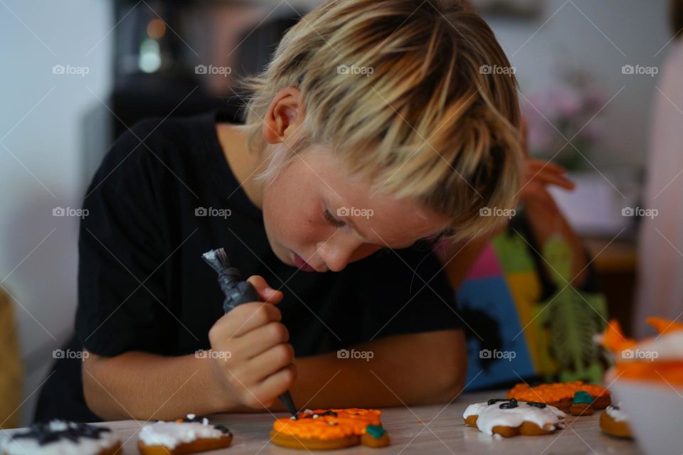 A seven year old child makes handmade cookies for Halloween.
