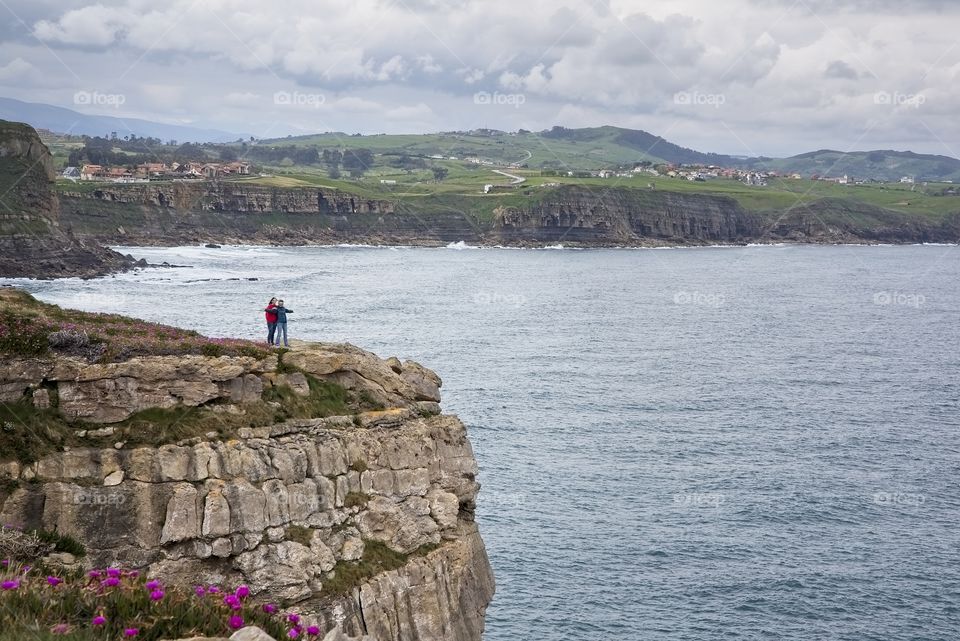 Two women on top of the cliff in Comillas, Spain