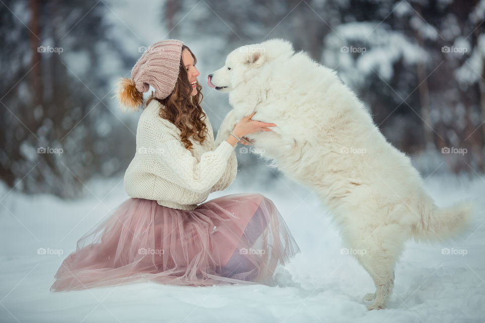 Beautiful woman with dog samoyed in winter forest