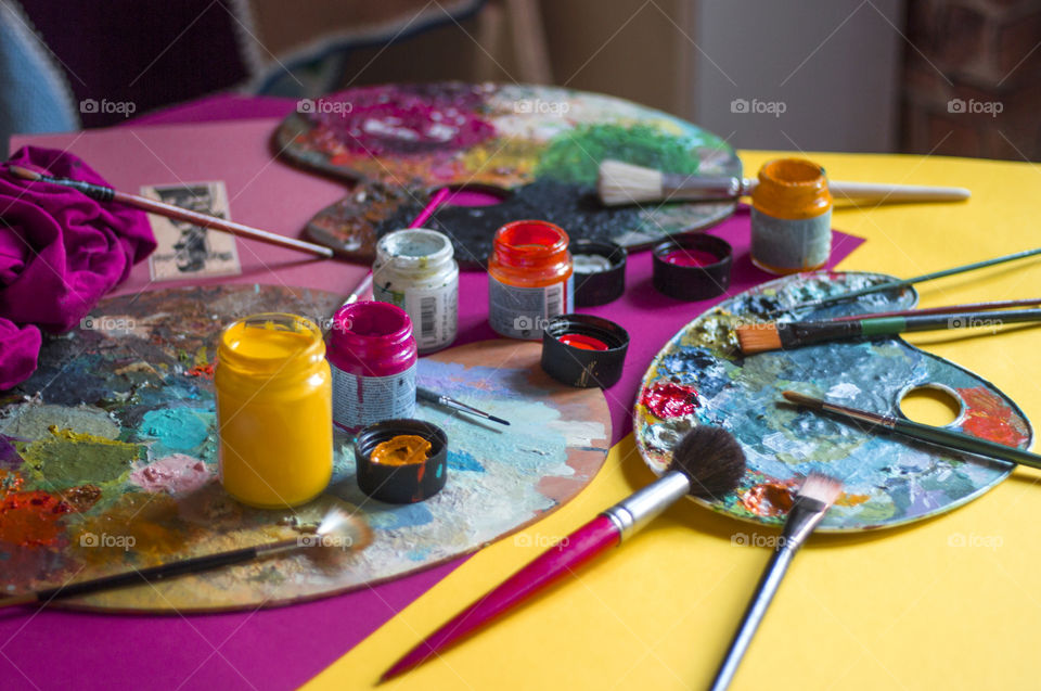 Colorful palette and paint containers on the desk