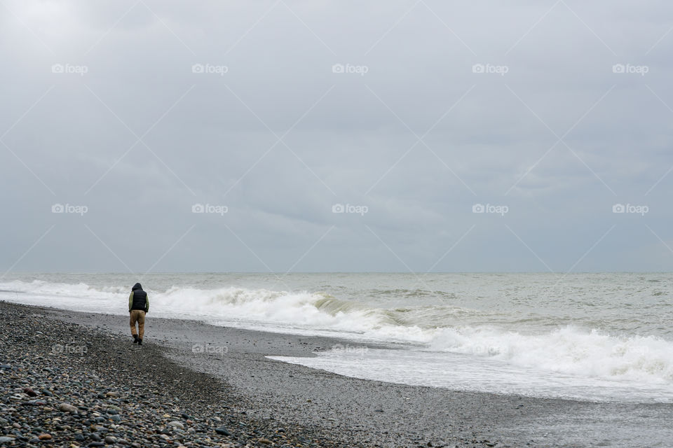 lonely man walking along the beach