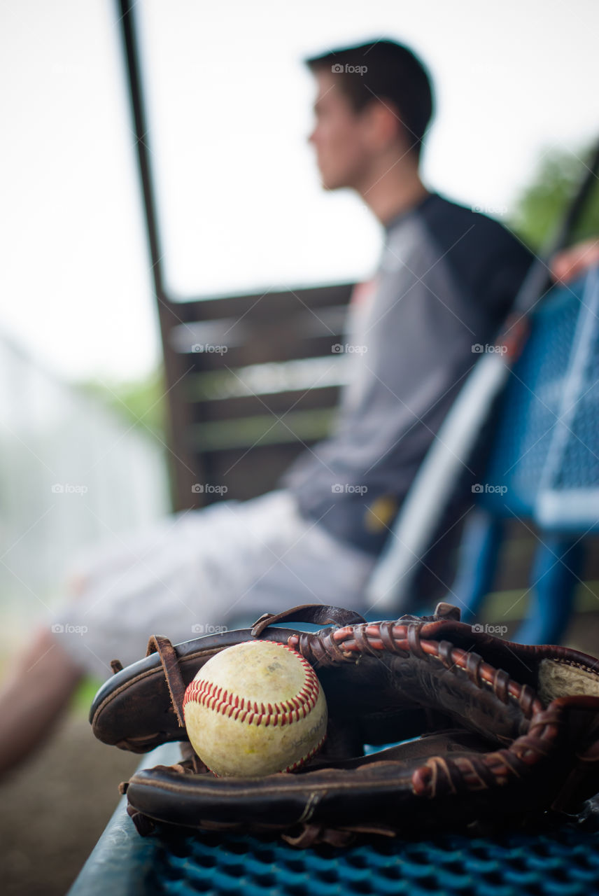 Young Man in Dugout with Baseball Mitt, Ball and Bat