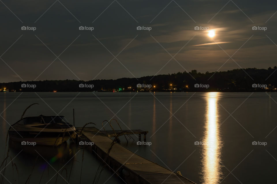 Beautiful night time landscape over the lake of Merrimac, MA. This was past the sunset so what you see there is actually the moon shinning the night. A dark scenery since it was taken after 8pm at night when it was getting dark outside. 