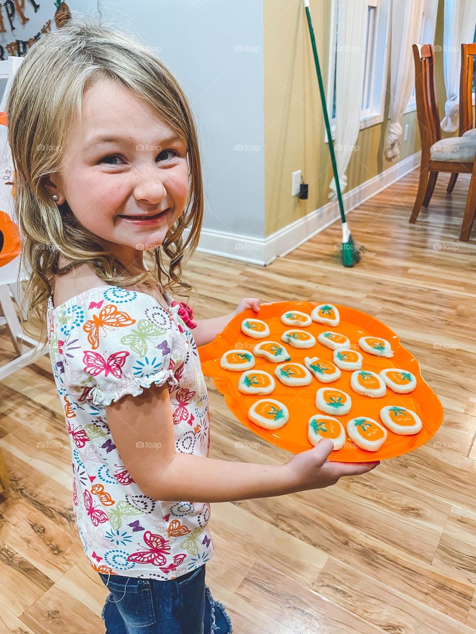 A girl holding a plate of pumpkin cookies