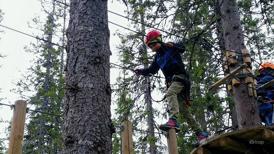 Boy walking on pole holding rope