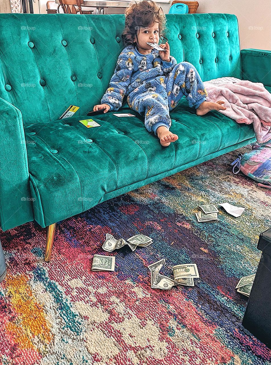 Toddler with look of disgust on couch, toddler disgusted with money, toddler shows emotion of disgust, toddler on couch with items strewn about, toddler empties wallet contents, funny toddler photo