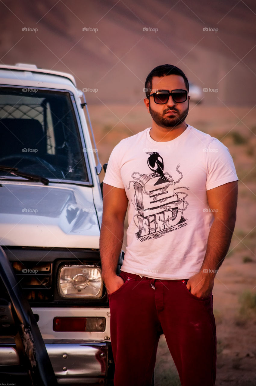 Lean on 4WD. Offroad trip to the desert with a handsome guy and his powerful patrol wearing sunglasses and look fashion