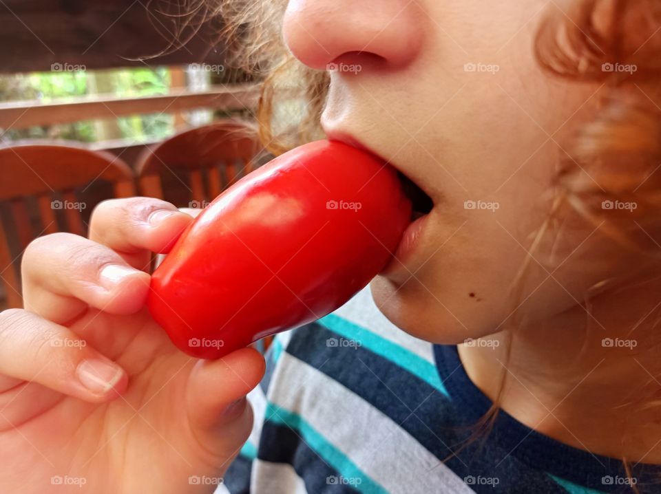 Girl eating tomato