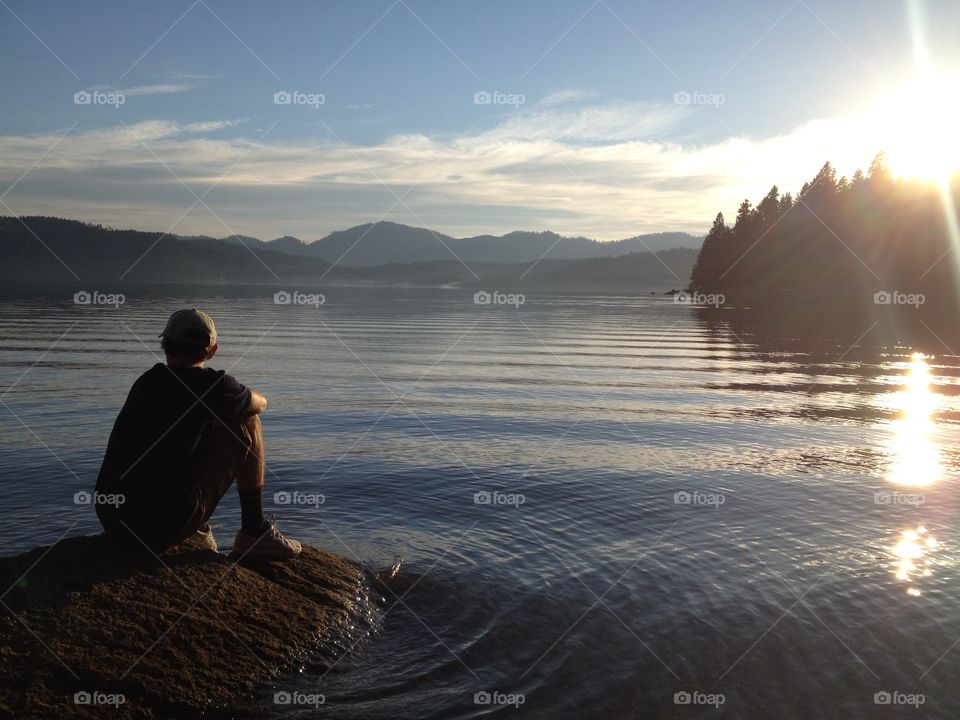 Boy sitting at edge of lake 
