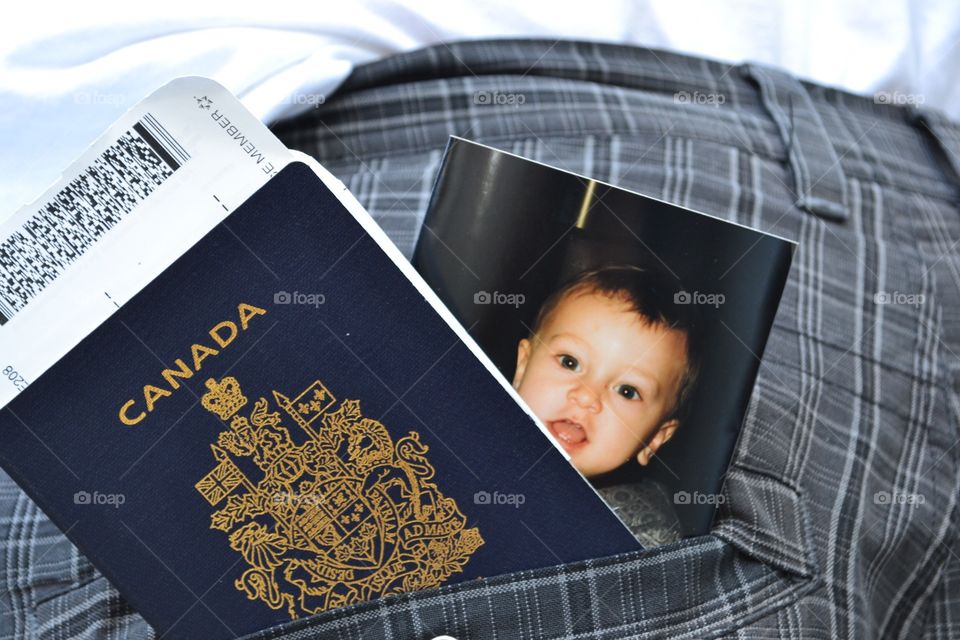 A father's single father's back pocket which holds his passport, boarding pass for flight  and photo of his son 