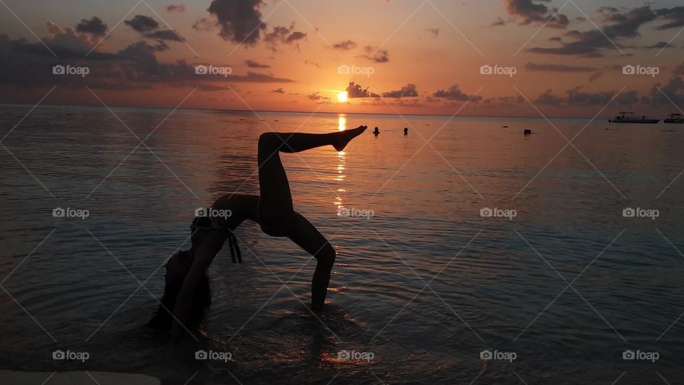 Woman doing acrobatics on the beach during sunset at negril, jamaica