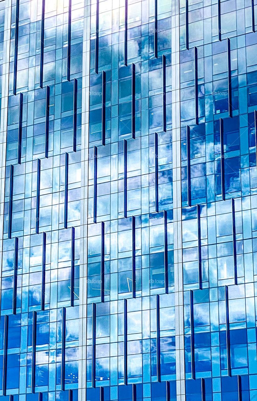 Blue sky reflected in modern glass and steel commercial office tower in a tech hub