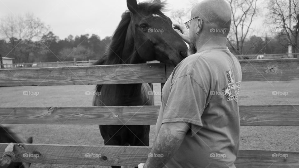 A man petting a horse at old Mac Donald's farm in humble Texas done in black and white