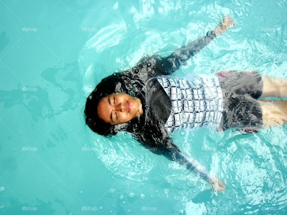 young girl floating in a swimming pool