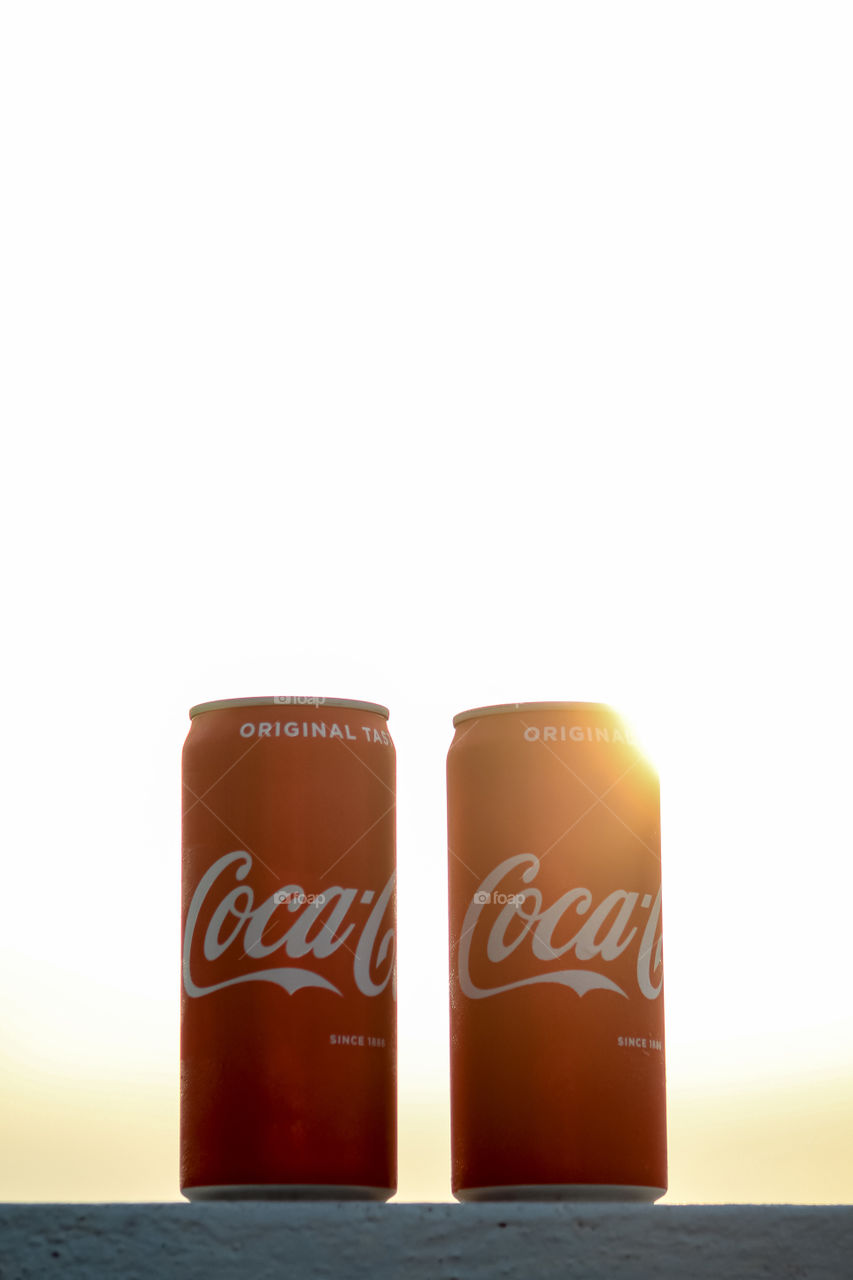 Coca-Cola tins with sun in the background 