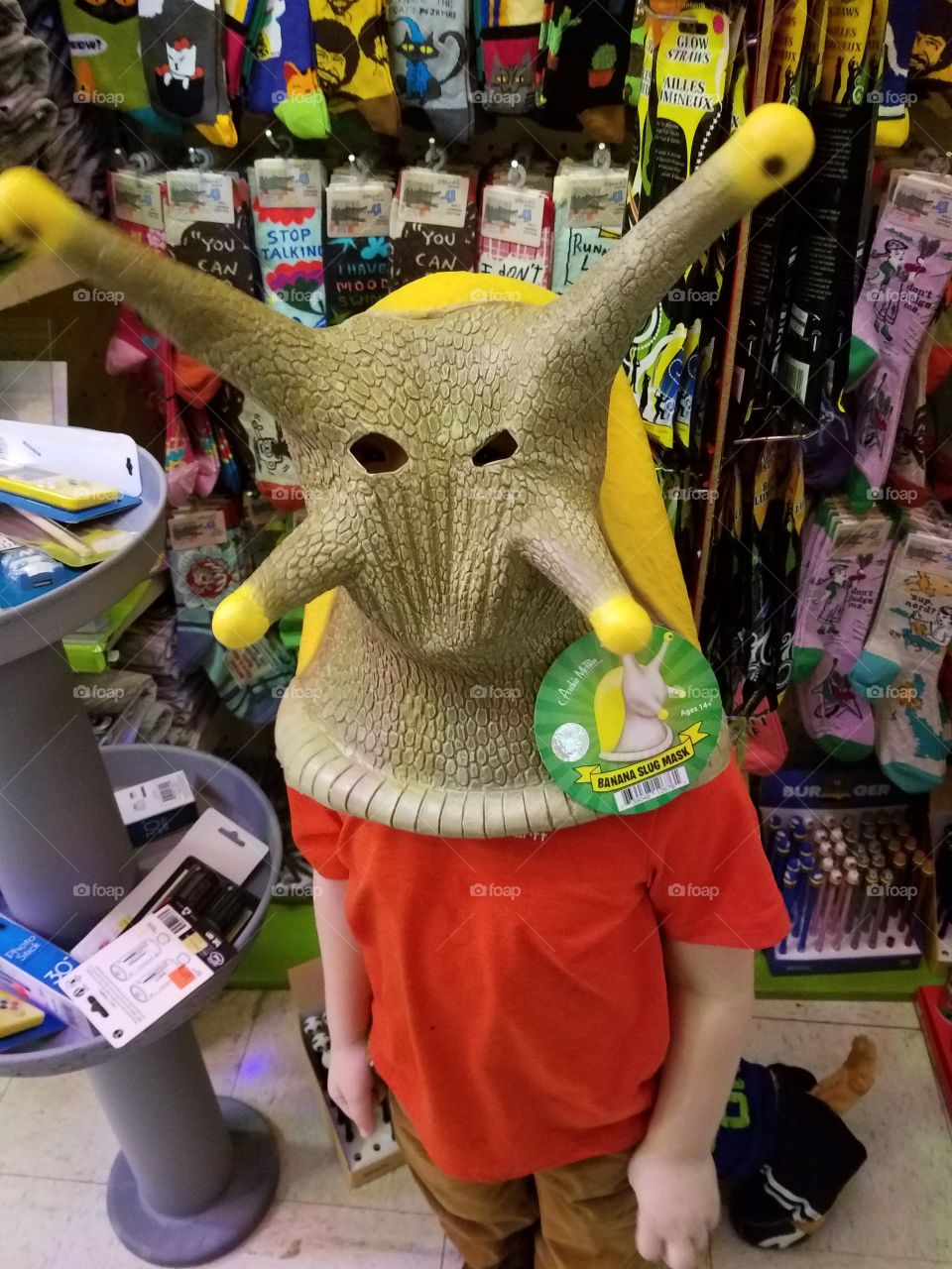 Little boy, standing in novelty store, proudly sports a sluggish disguise.