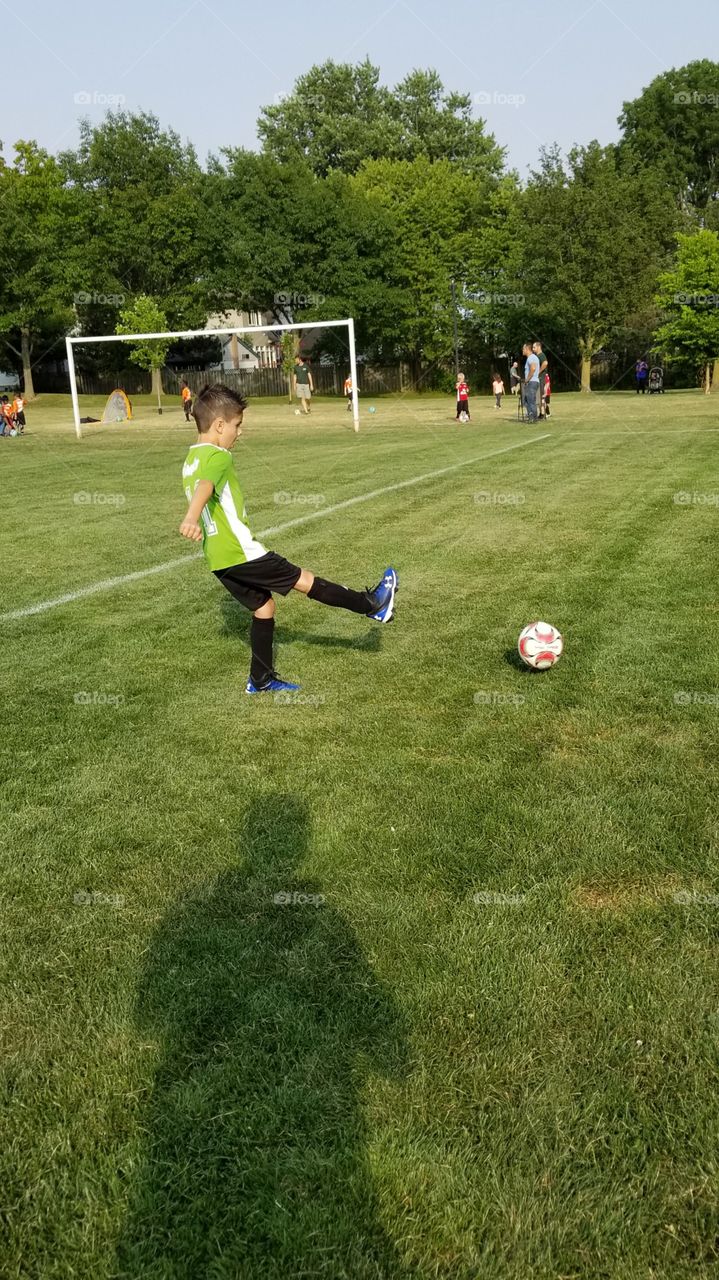 boy kicks soccer ball happy