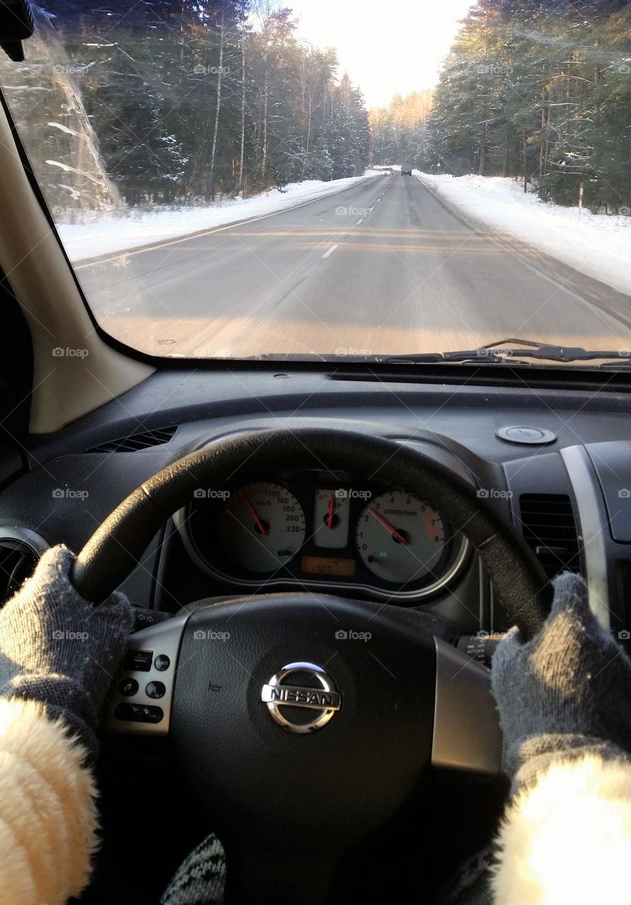 Inside the car is warm and comfortable. The winter road doesn't seem so dull any more. A female driver is driving home after work.