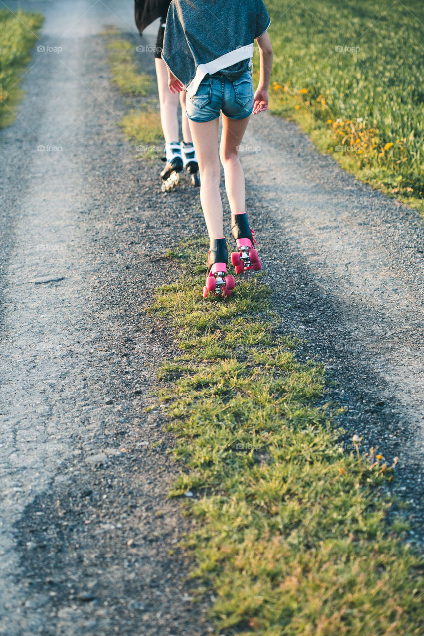 Teenage girl having fun rollerskating, jumping, spending time on summer day. Teenage smiling happy girls having fun walking outdoors, hanging, spending time together on summer day. Real people, authentic situations