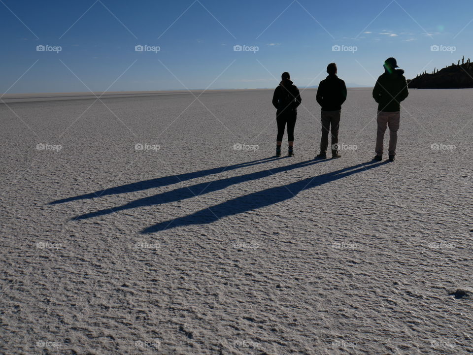 Three people and their shadows on Salar de Uyuni in Bolivia