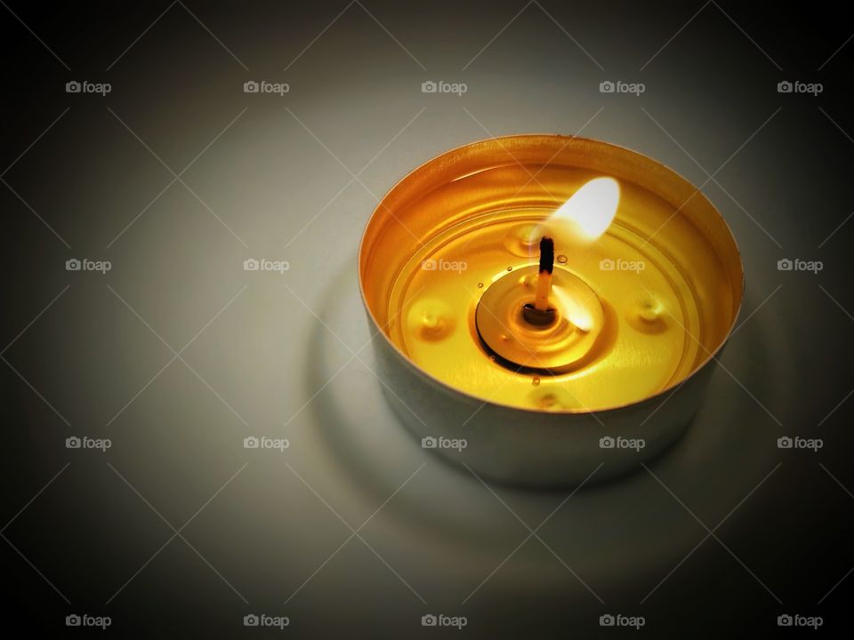 Tealight candle with blurred dark background.