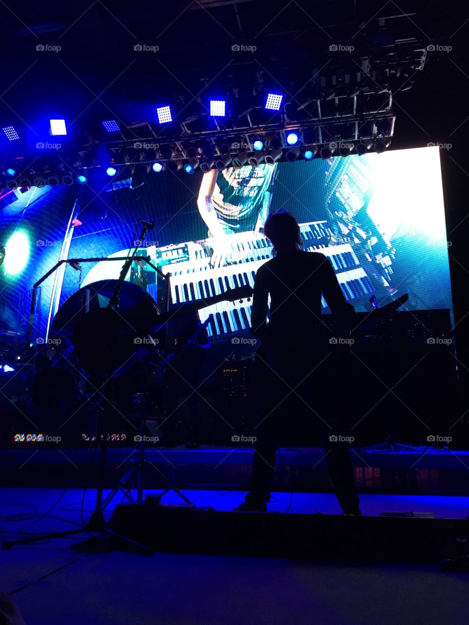 Boston guitarist Tom Scholz on stage, performing a keyboard solo against a video backdrop at the Saint Augustine amphitheater in Florida May 24, 2015