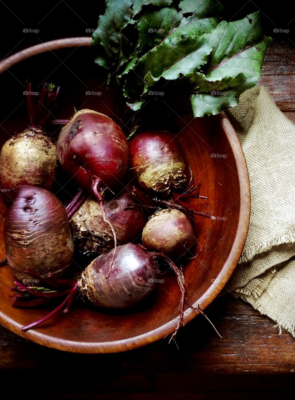 Fresh picked red beets and greens in a wooden bowl. 