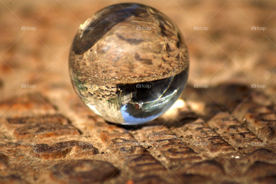 Lensball sitting on the ground, reflecting an old car and the blue sky