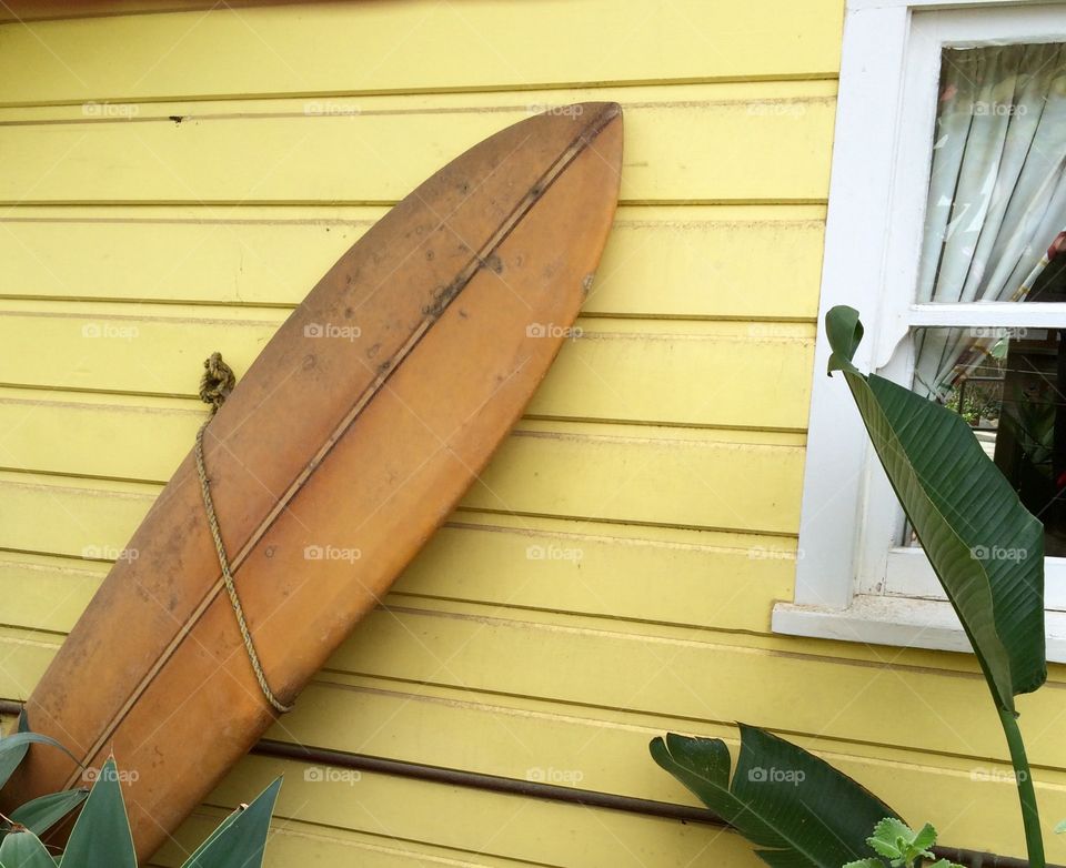 Surfboard  alongside beach house.  