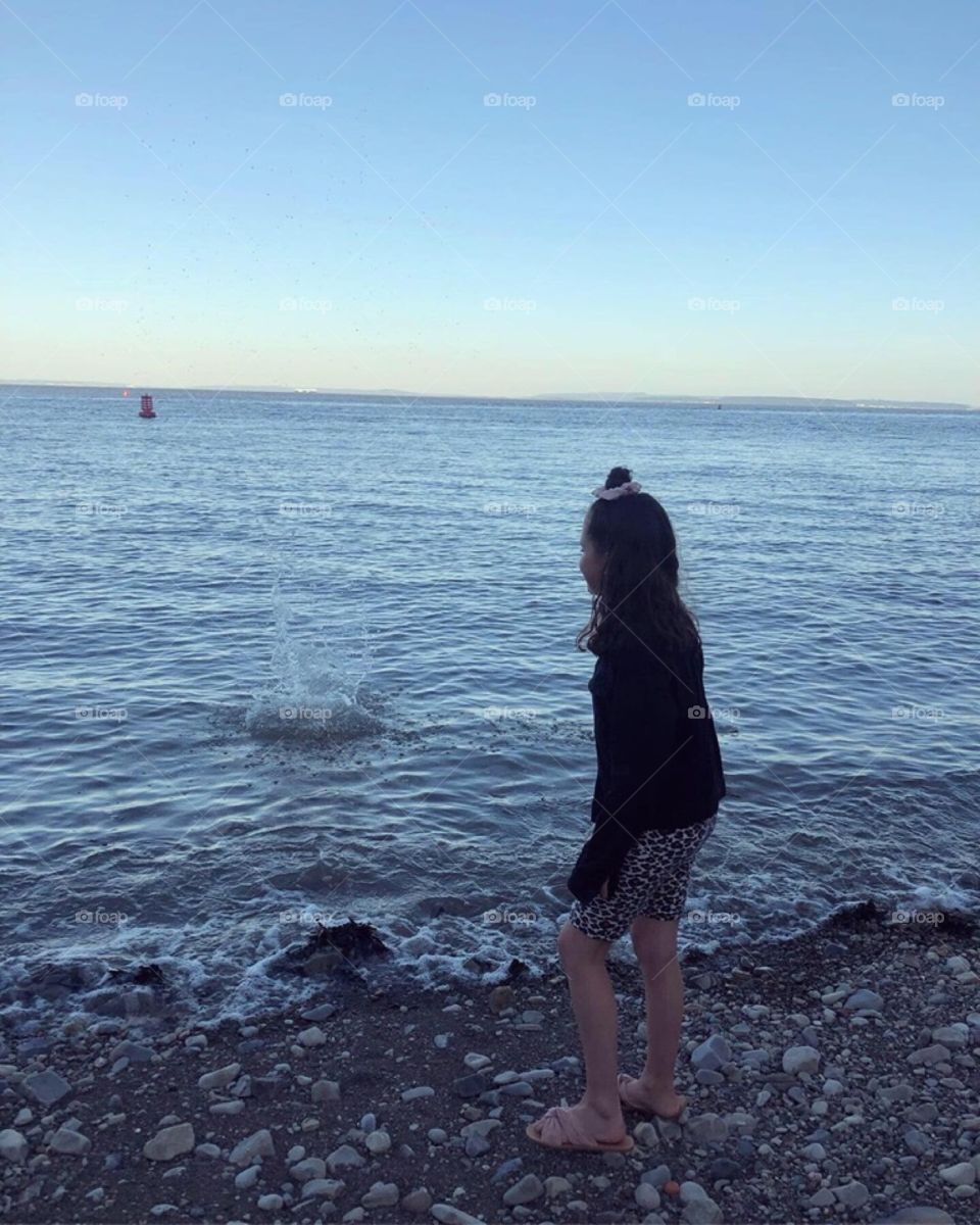 Girl stood by the water at sunset 