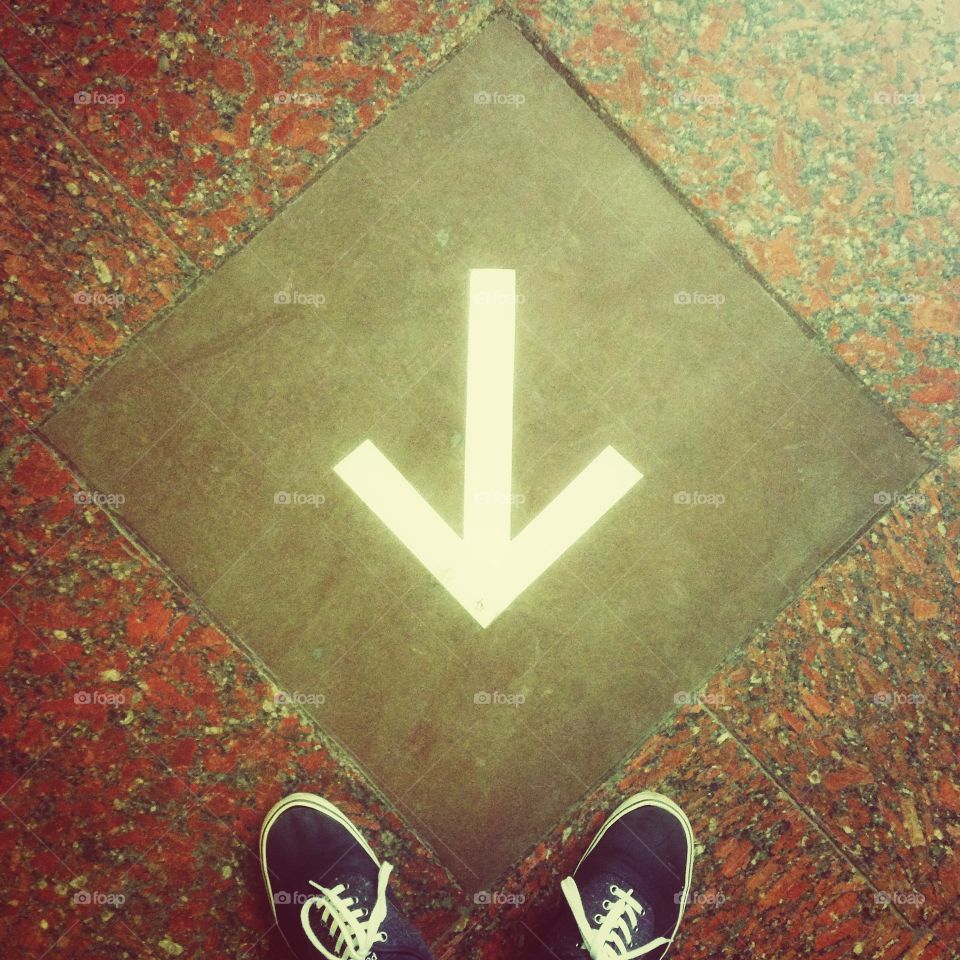 Blue shoes in front of the white arrow on the floor