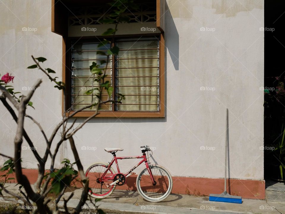 A forgotten children bicycle resting at the back of the house