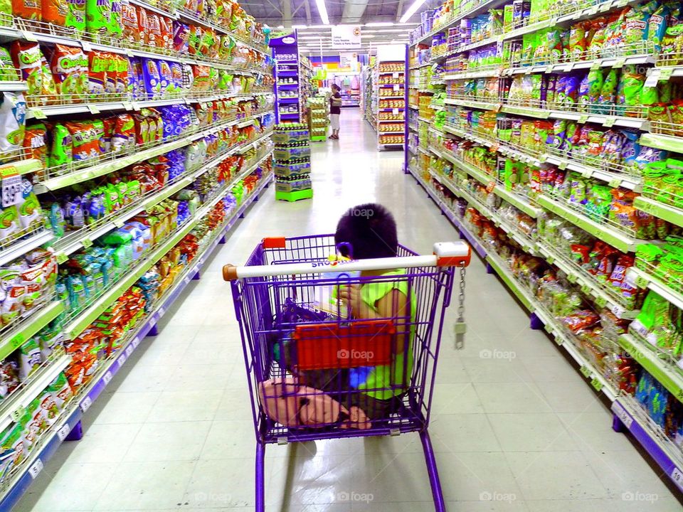 asian child riding a grocery cart in a grocery