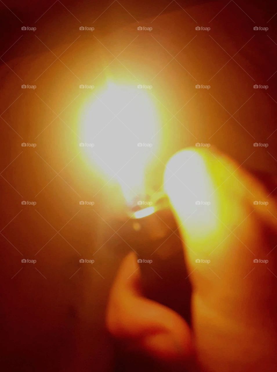 Lighter flame in a dark room with a brown background