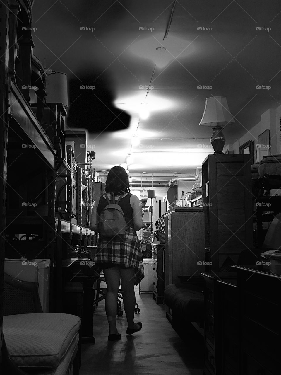 Girl trying to navigate a thrift shop. B&W.