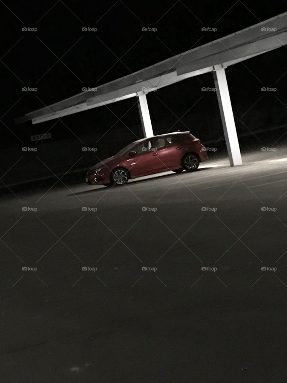 A red vehicle in an empty church parking lot on a quiet night.