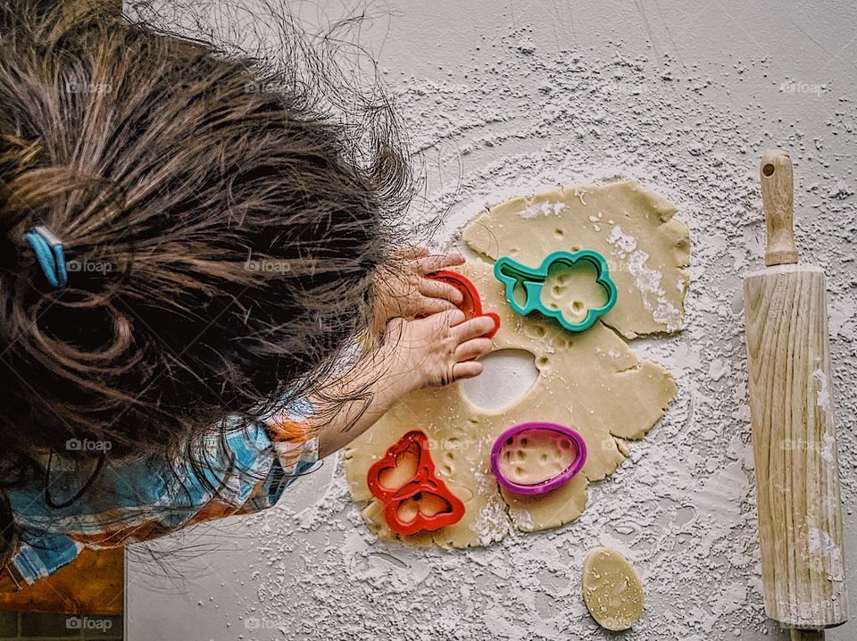 Toddler girl makes sugar cookies, toddler girl helps mommy in the kitchen, toddler bakes cookies with mommy, homemade sugar cookies for Easter, making sugar cookies for Easter, toddler uses cookie cutters to make shapes in dough, overhead shot 