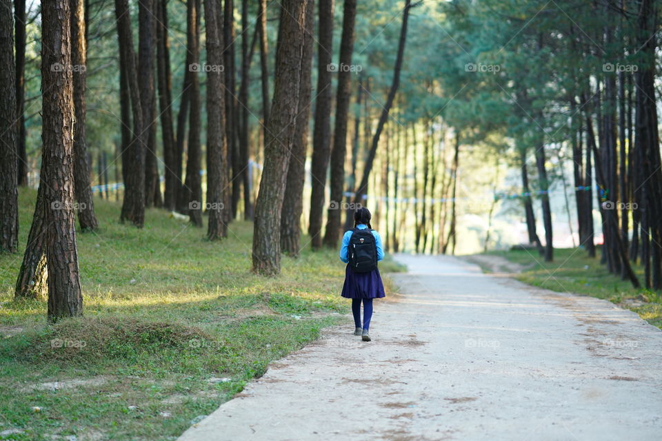 School girl walking on footpath in forest