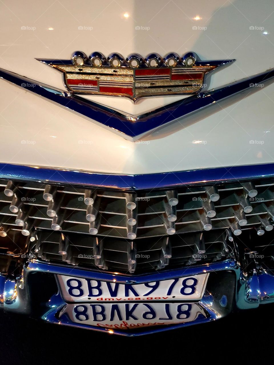 A classic Cadillac has shiny chrome that mirrors its license plate