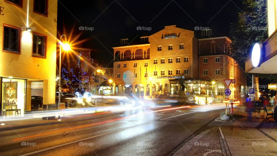 Dark Street in Munich late autumn sometimes with lights lit storefronts and shops long loops beam passing through the intersection of cars.